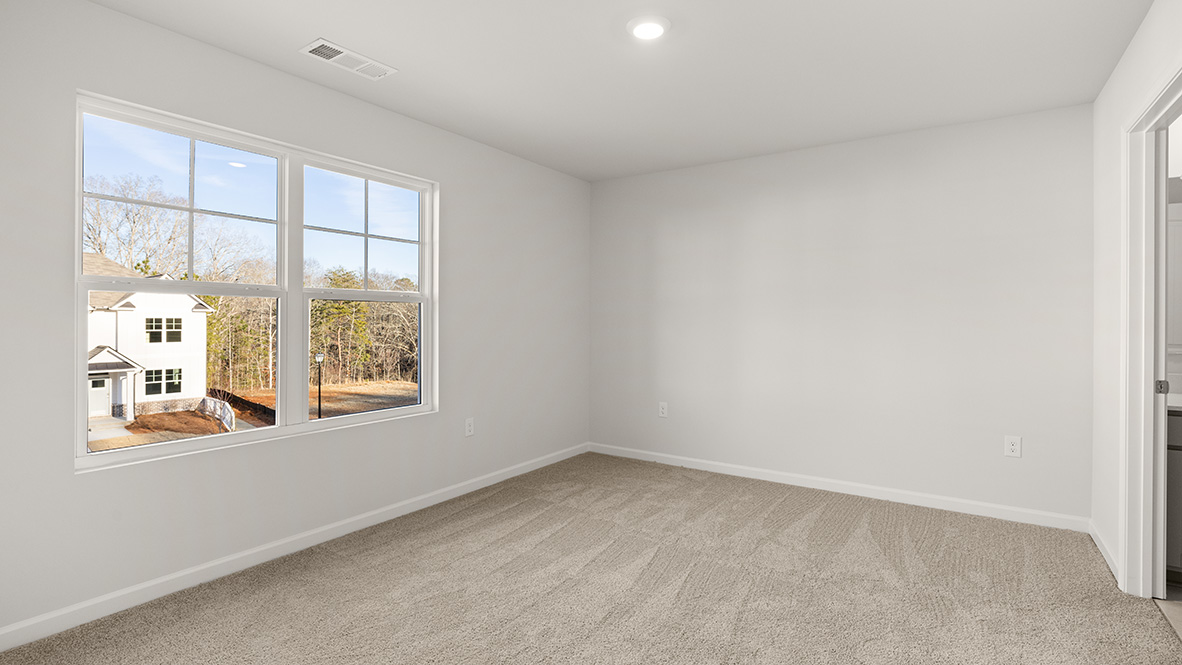 bedroom with beige carpet, white walls and a window