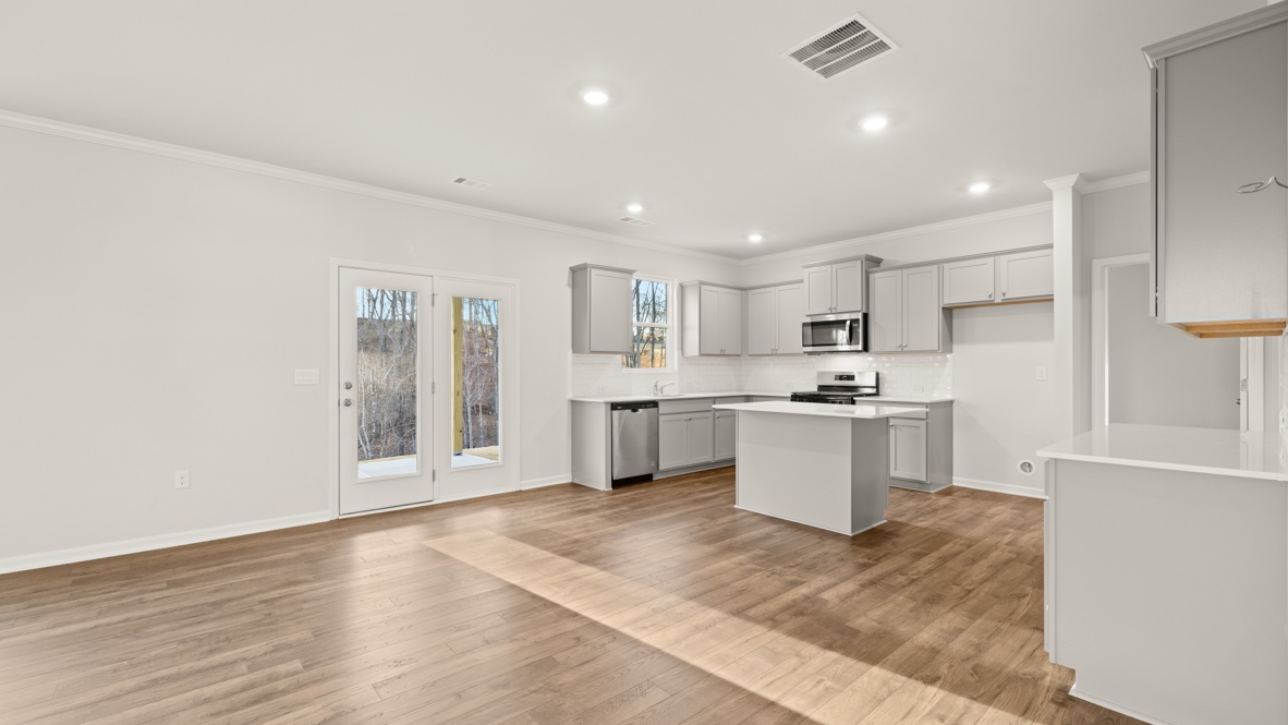 Interior living area open to kitchen with center island and light grey cabinets