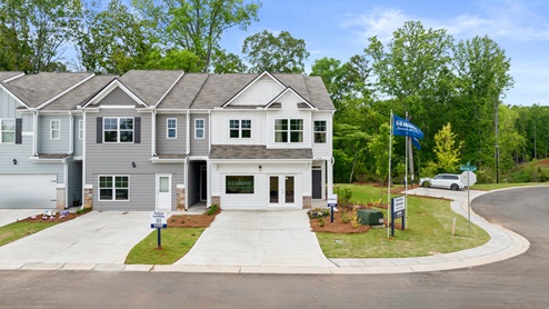 Two-story home with two gables, three windows and a small front porch over the doorway with a front door with a transom.