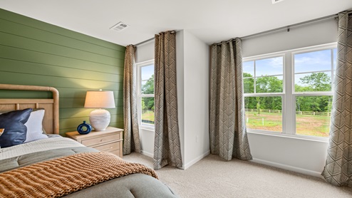 Bedroom with neutral carpet. with a single window and a double window.