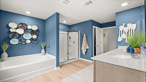 Ensuite bathroom with a white garden tub, a white walk-in shower with a glass door and a double vanity sink with granite countertops and natural color wood beveled flat panel cabinets.