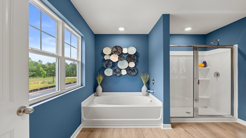 Ensuite bathroom with white garden tub, white walk-in sjhower with glass door and a double window.