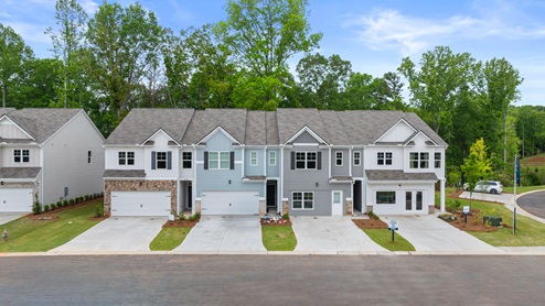 Two-story home with two gables, three windows and a small front porch over the doorway with a front door with a transom.