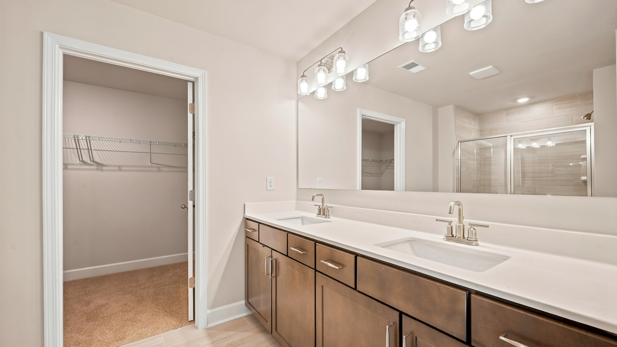 primary bathroom with dual sinks and primary walk-in closet