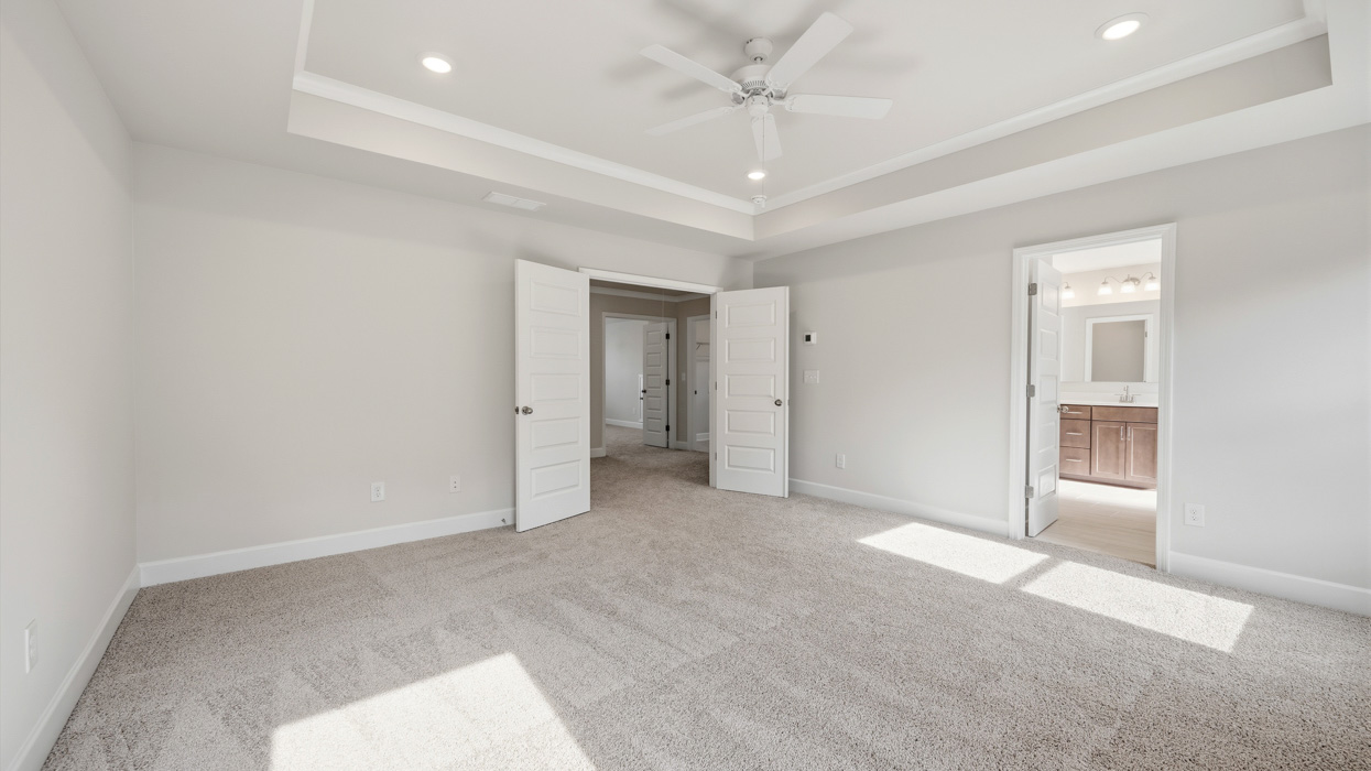 angled primary bedroom with natural light and ceiling fan