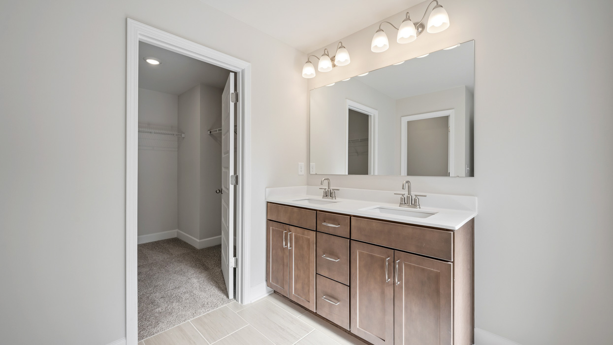 primary bathroom with dual sinks and walk-in closet
