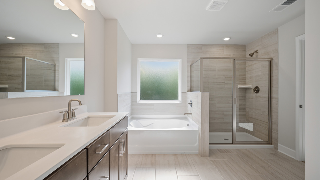 primary bathroom with dual sinks natural light and walk-in shower and tub
