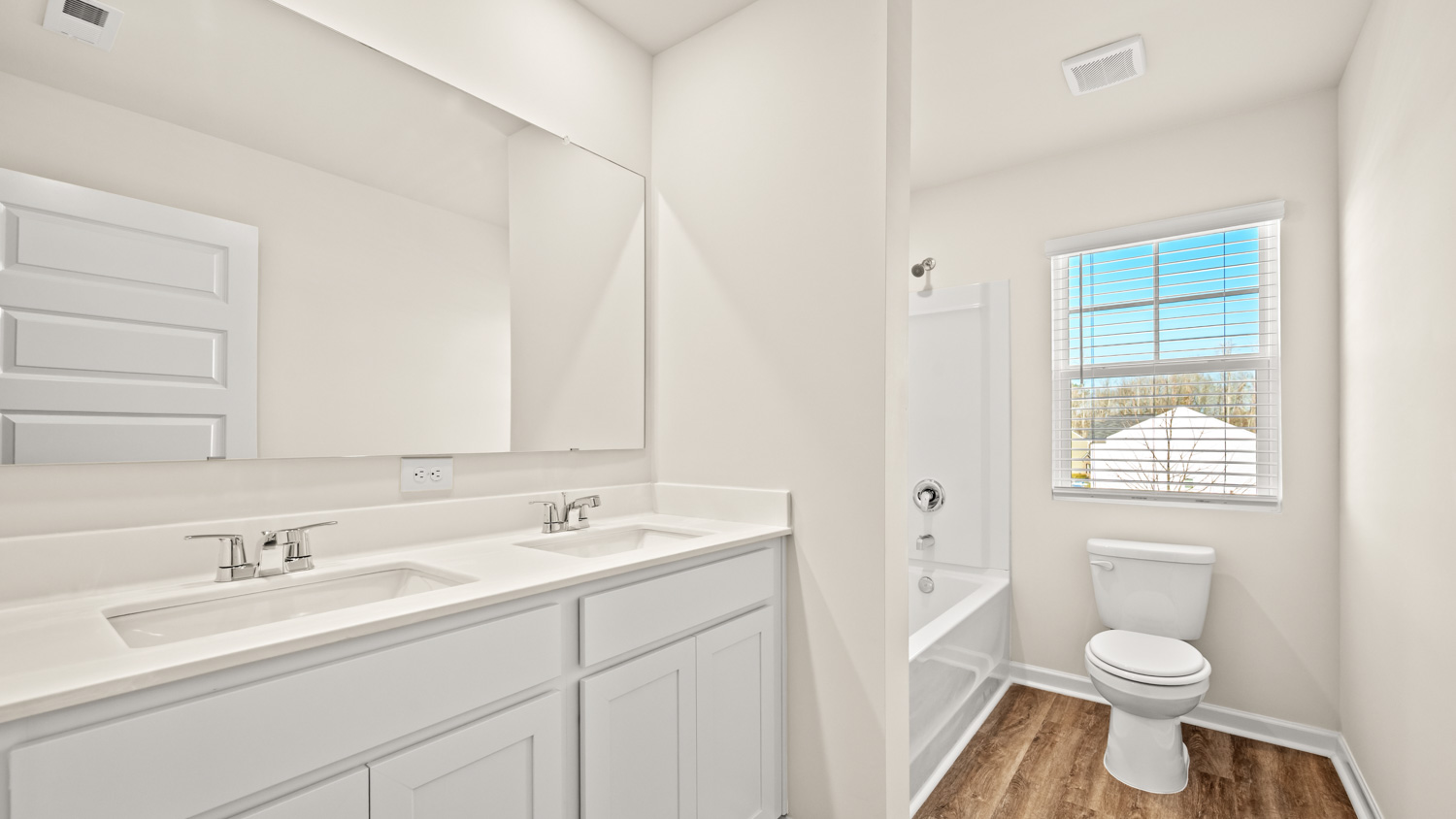 bathroom with dual sinks and natural light