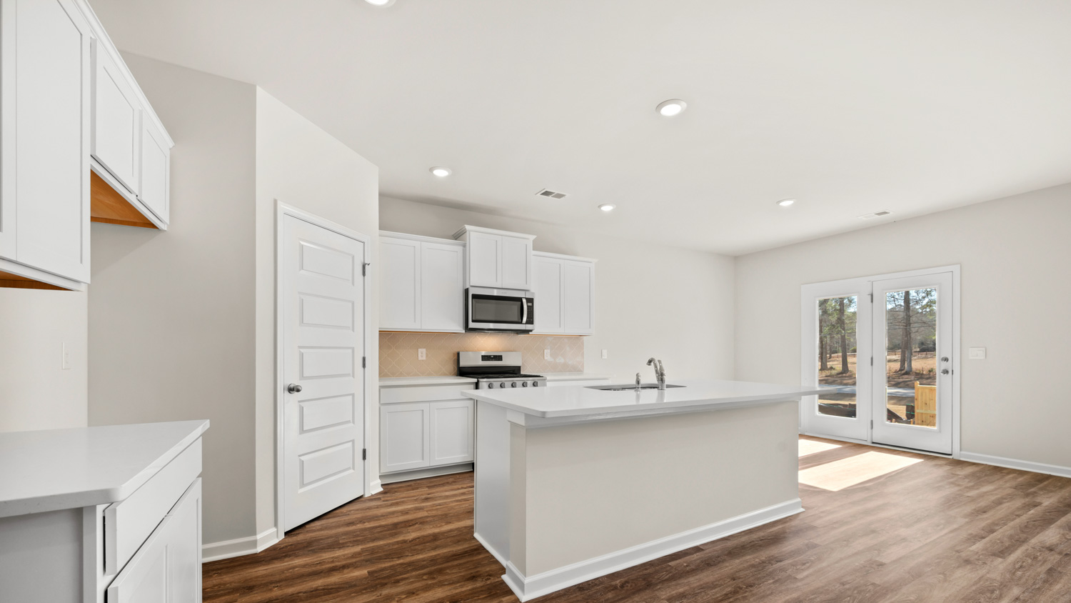 angled kitchen with large center island and spacious white cabinets