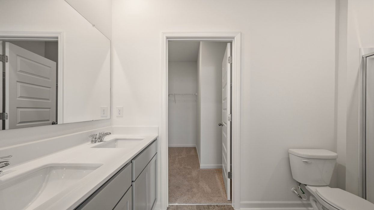 primary bathroom with dual sinks and walk-in closet