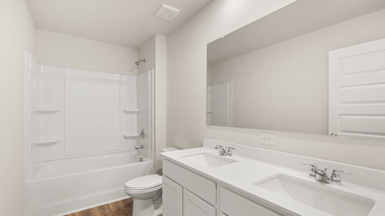 bathroom with dual sinks and bathtub