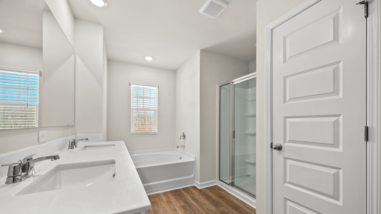 primary bathroom with dual sinks with a walk-in shower and tub