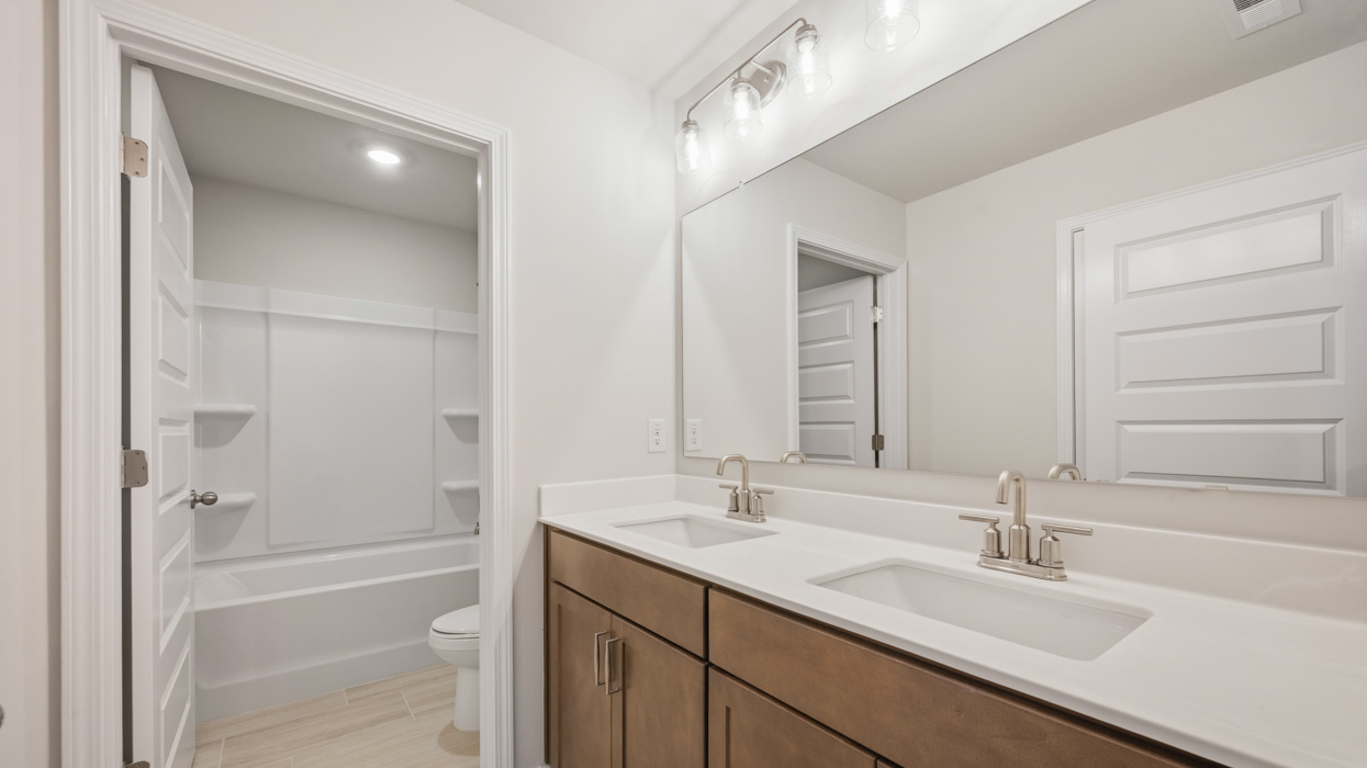 bathroom with dual sinks and water closet with tub