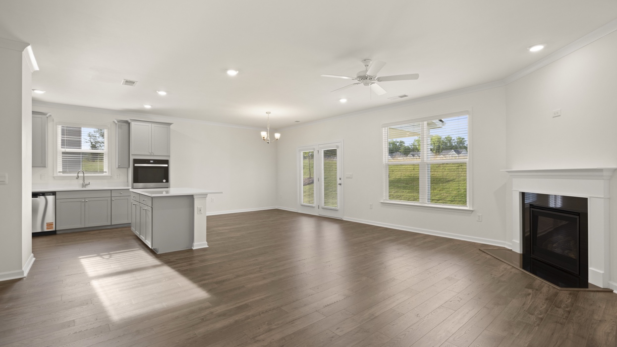 gathering room with fireplace natural lighting looking into the kitchen