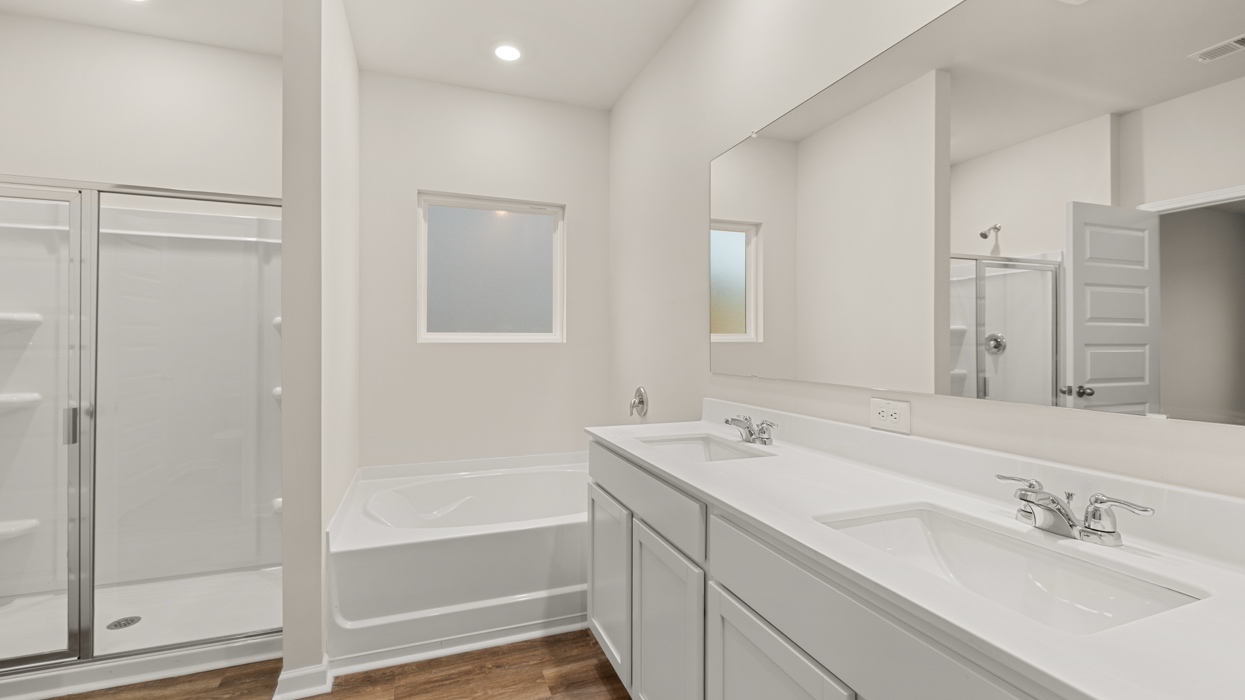 angled primary bathroom with dual sinks and natural light