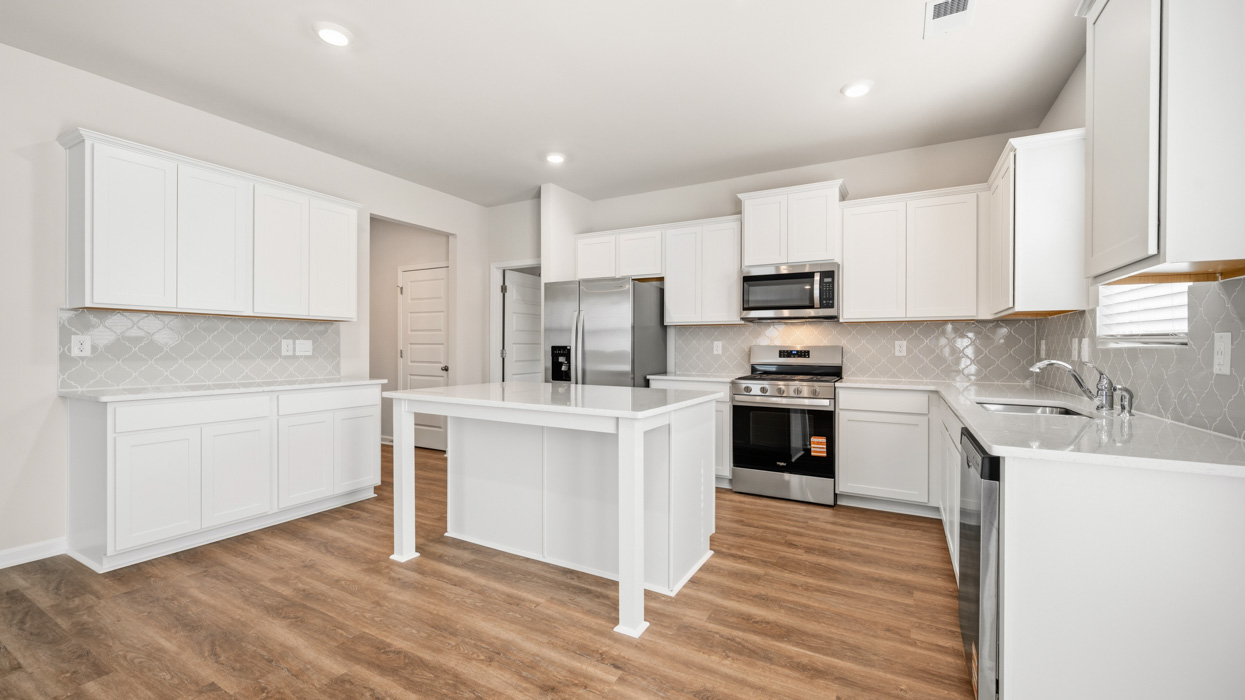 angled kitchen with large center island and spacious white cabinetry