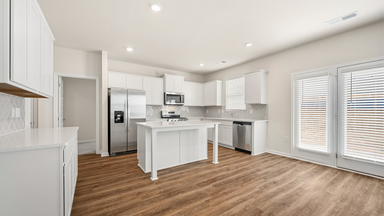 angled kitchen with large center island and spacious white cabinetry with access to back patio