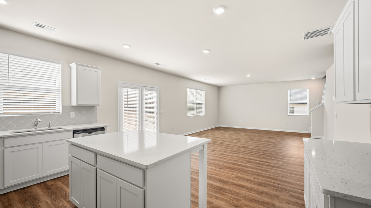 angled living room from kitchen with access to back patio and natural light