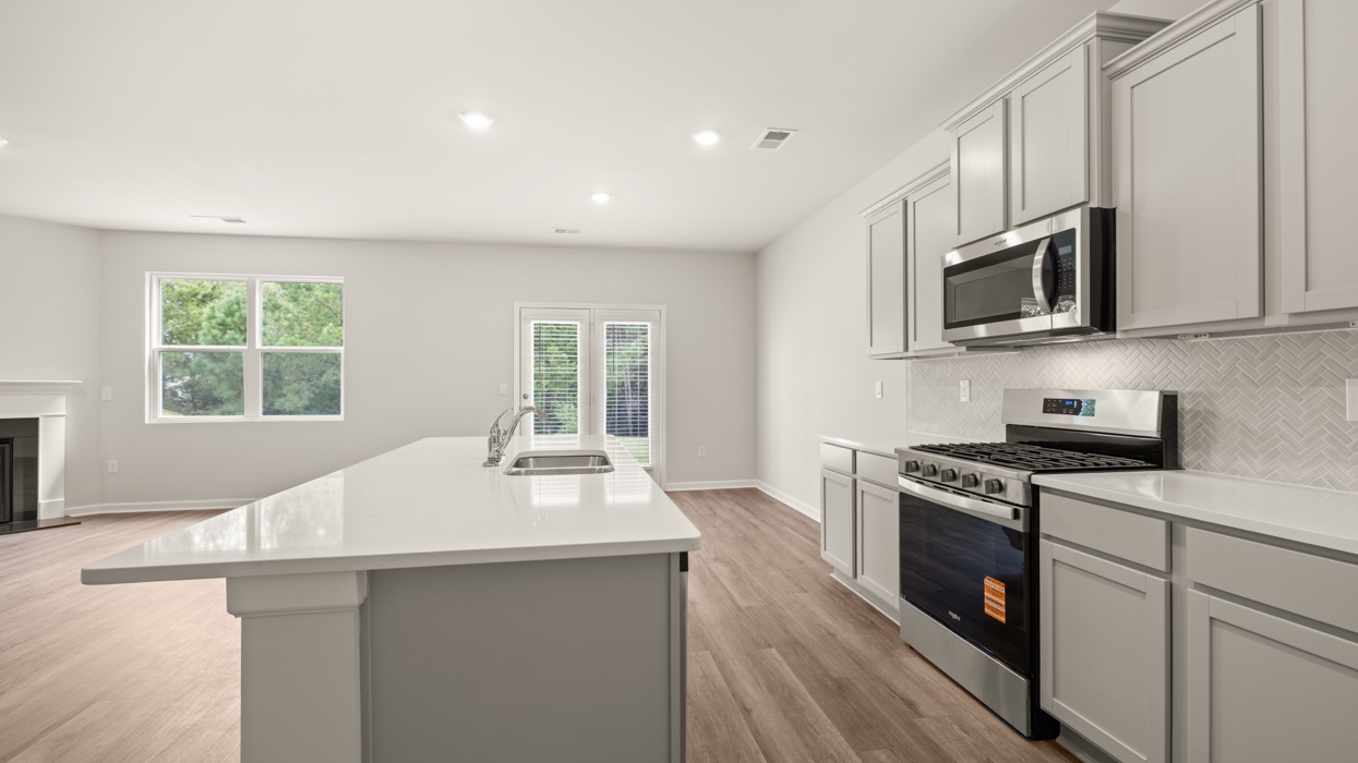 angled kitchen with large center island with spacious gray cabinetry