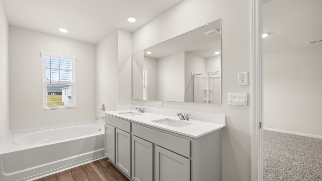 primary bathroom with dual sinks and tub with natural light
