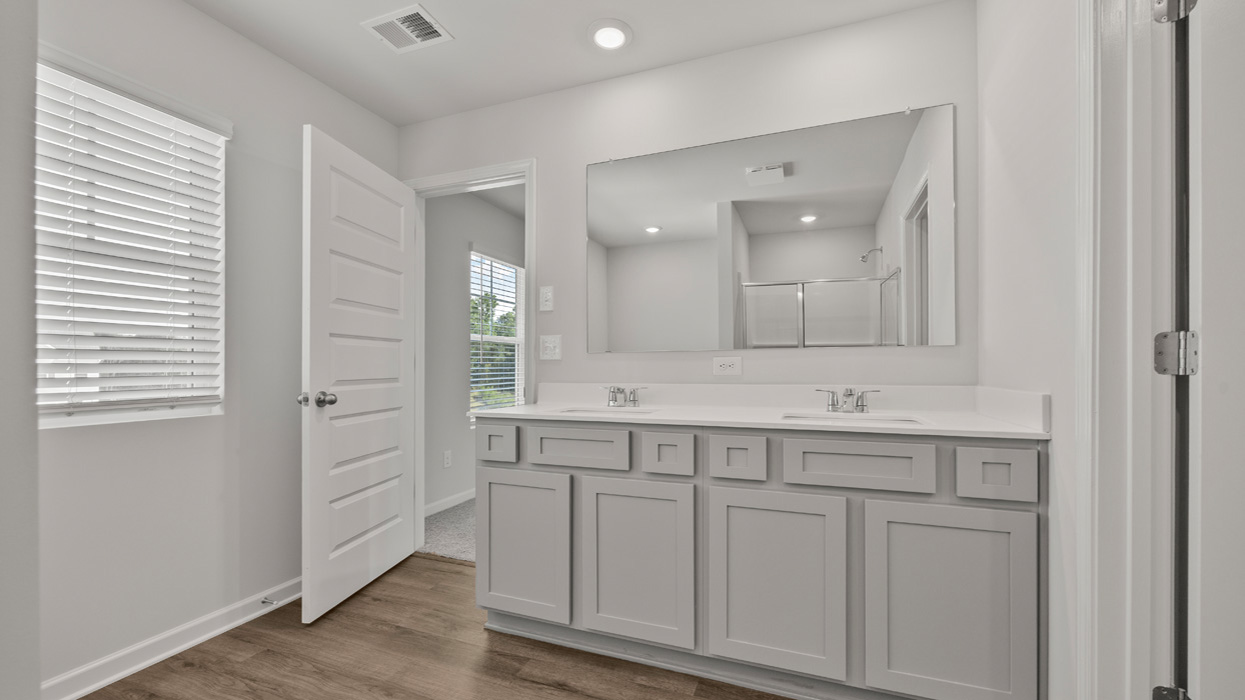 angled primary bathroom with dual sinks and natural light