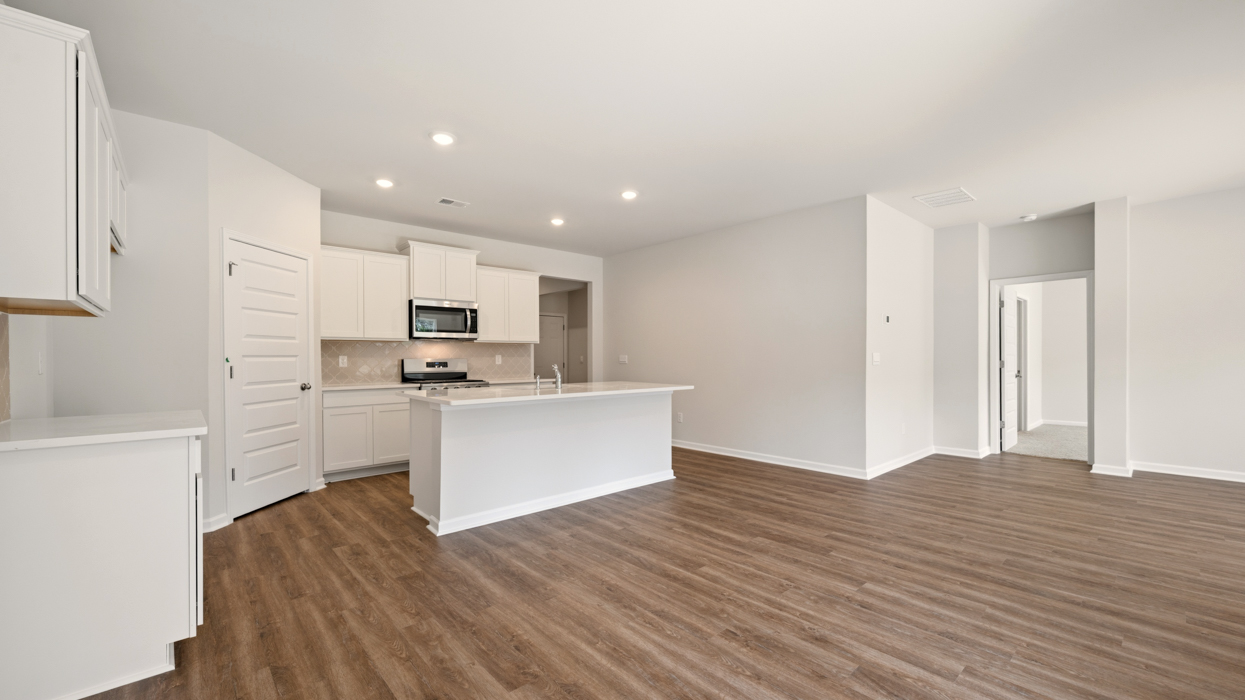 angled kitchen with spacious white cabinetry and large center island from breakfast room