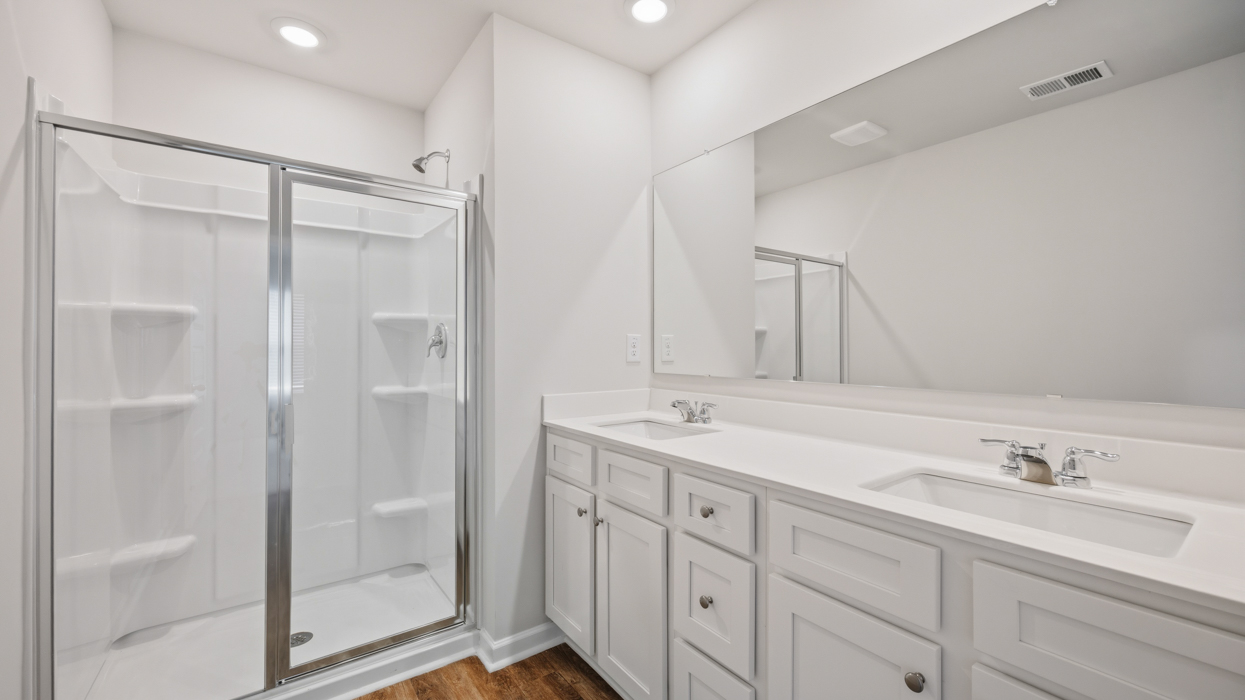 primary bathroom with dual sinks and walk-in shower