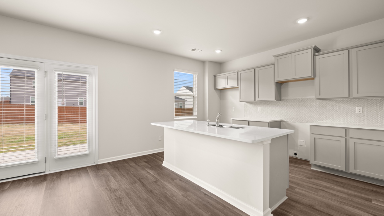 angled kitchen with spacious grey cabinetry and large center island with rear patio access