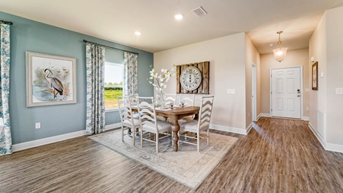 Dining room table and chairs with window and foyer entrance.