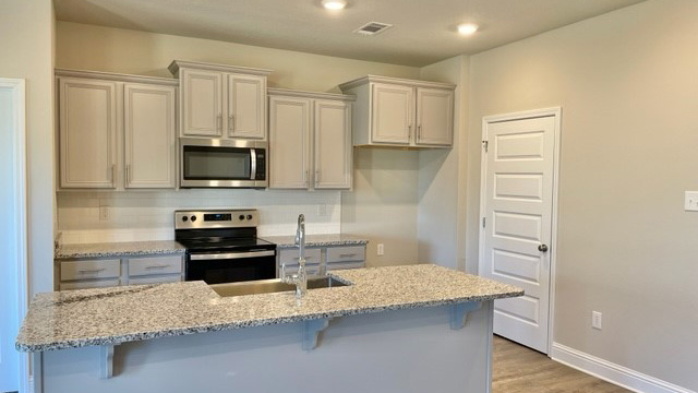 Shaker style kitchen cabinetry and island with granite countertops.
