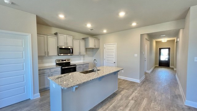Shaker style kitchen cabinetry and island with granite countertops.
