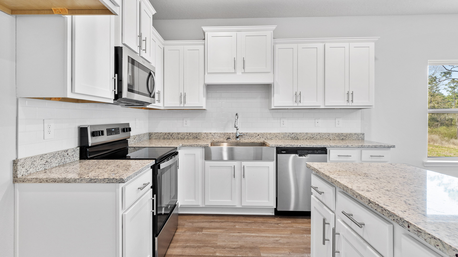 Stunning white kitchen with granite countertops in an open kitchen layout.