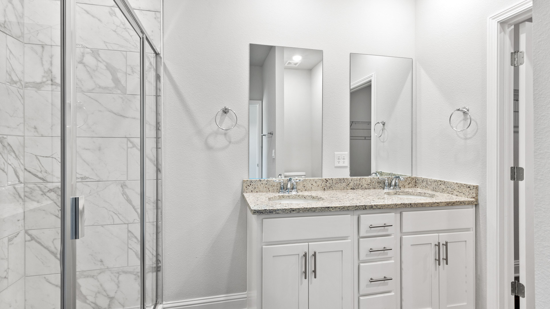 Primary bathroom with white cabinets and granite countertops.