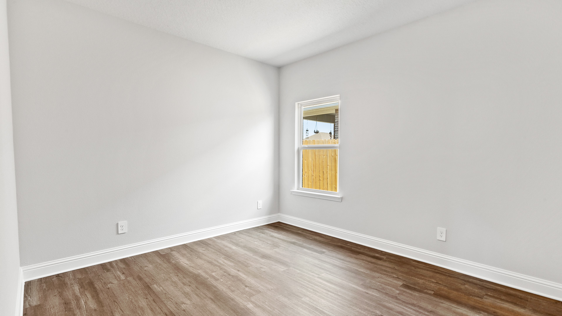 Guest bedroom with luxury vinyl plank flooring and neutral paint colors.