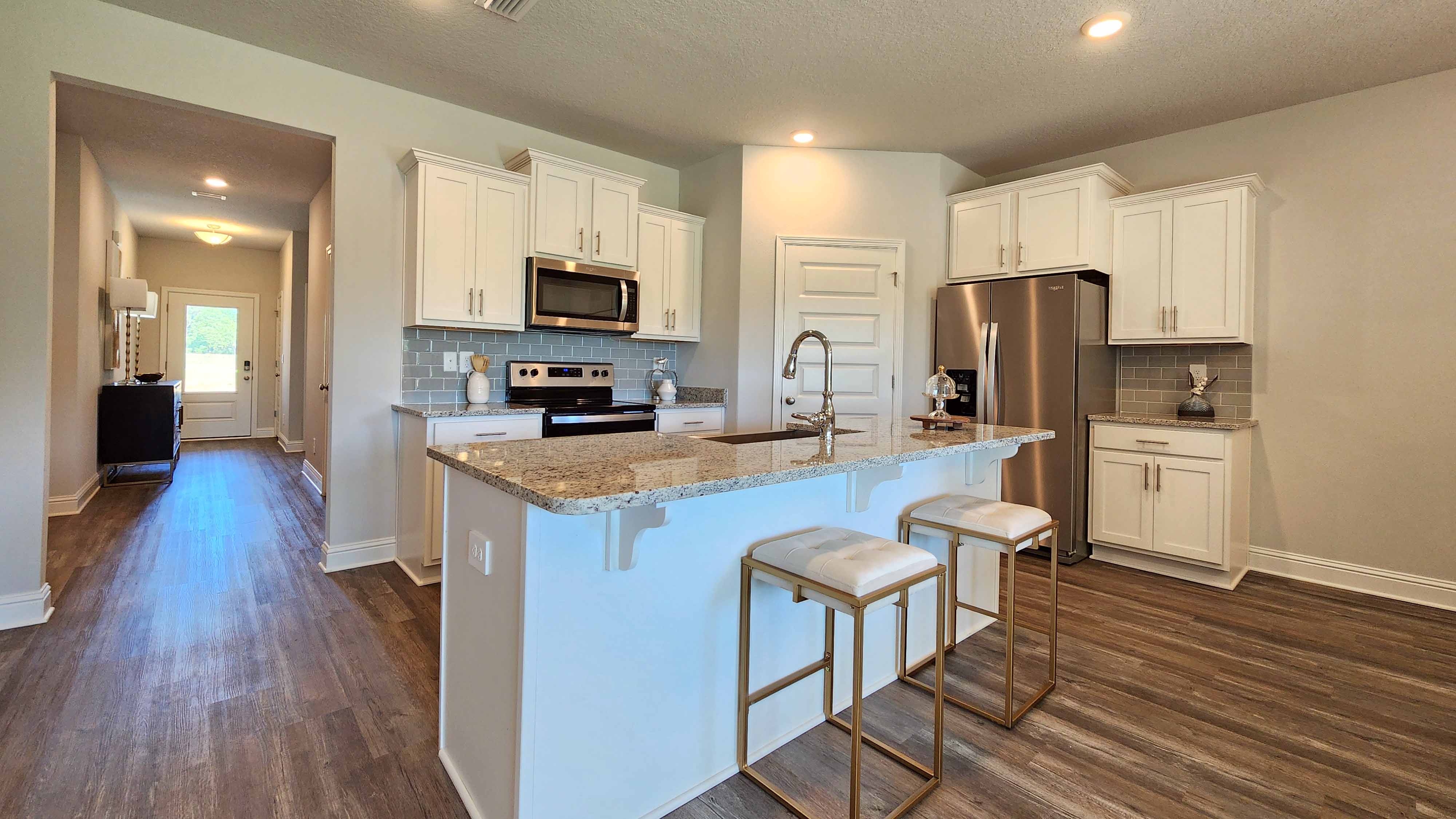 Kitchen with white shaker style cabinetry and island with seating.