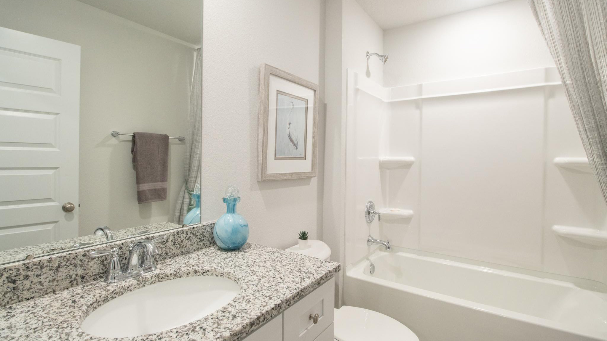 The guest bathroom with vanity and granite counter and shower/tub combination.