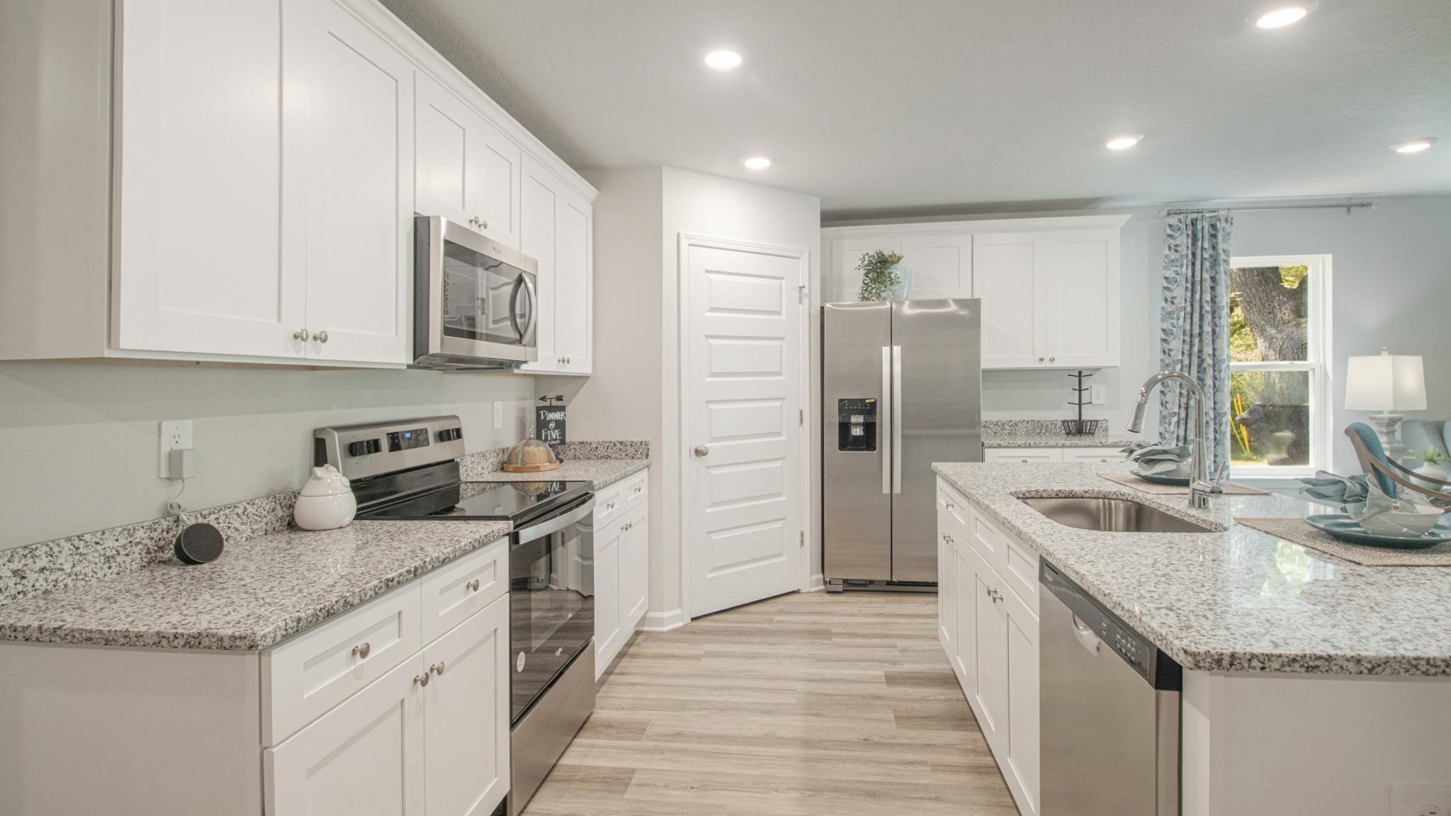 The kitchen with white shaker-style cabientry and island with granite countertop.