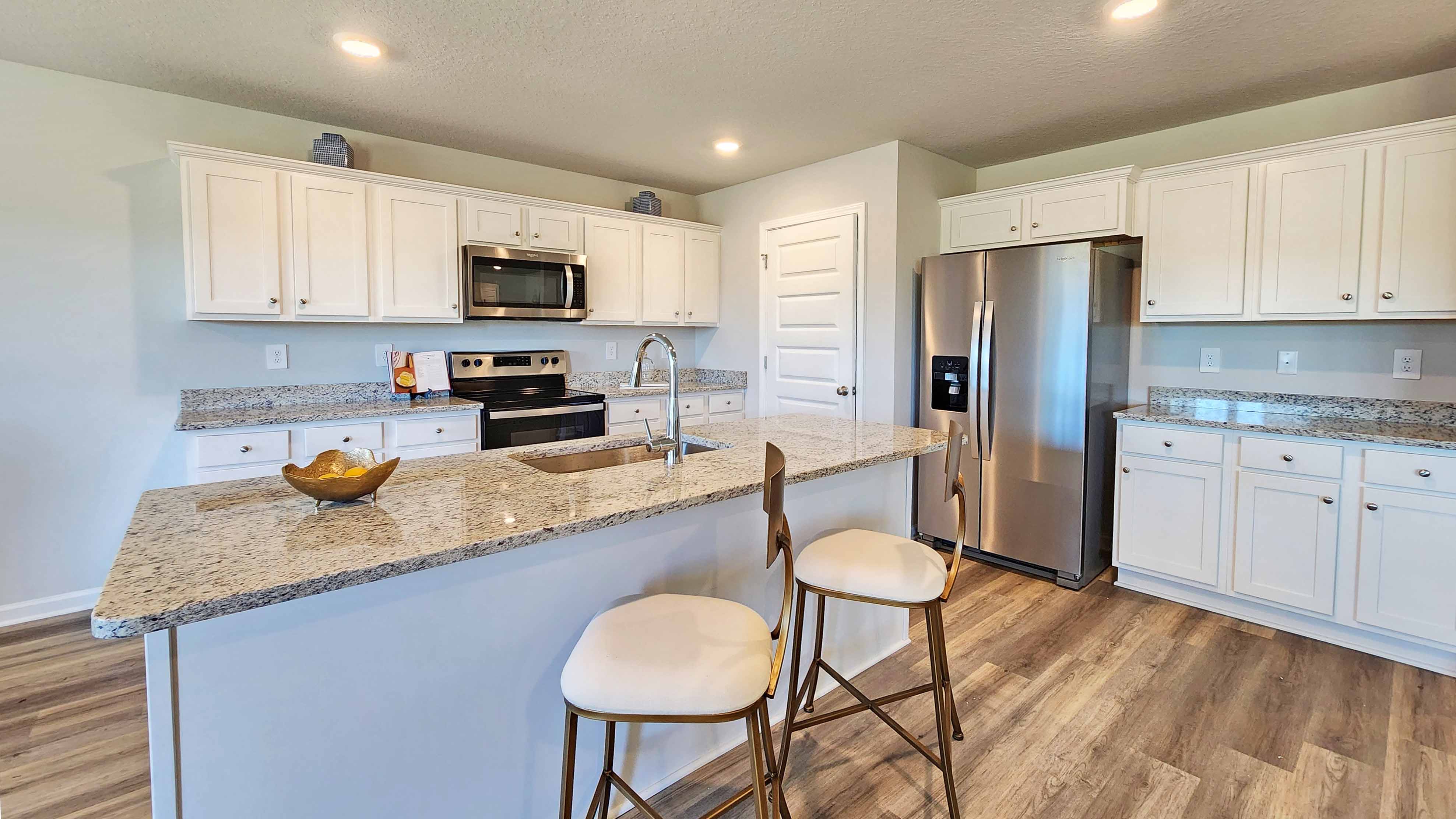 The Denton kitchen with white shaker-style cabinetry and granite counter island.