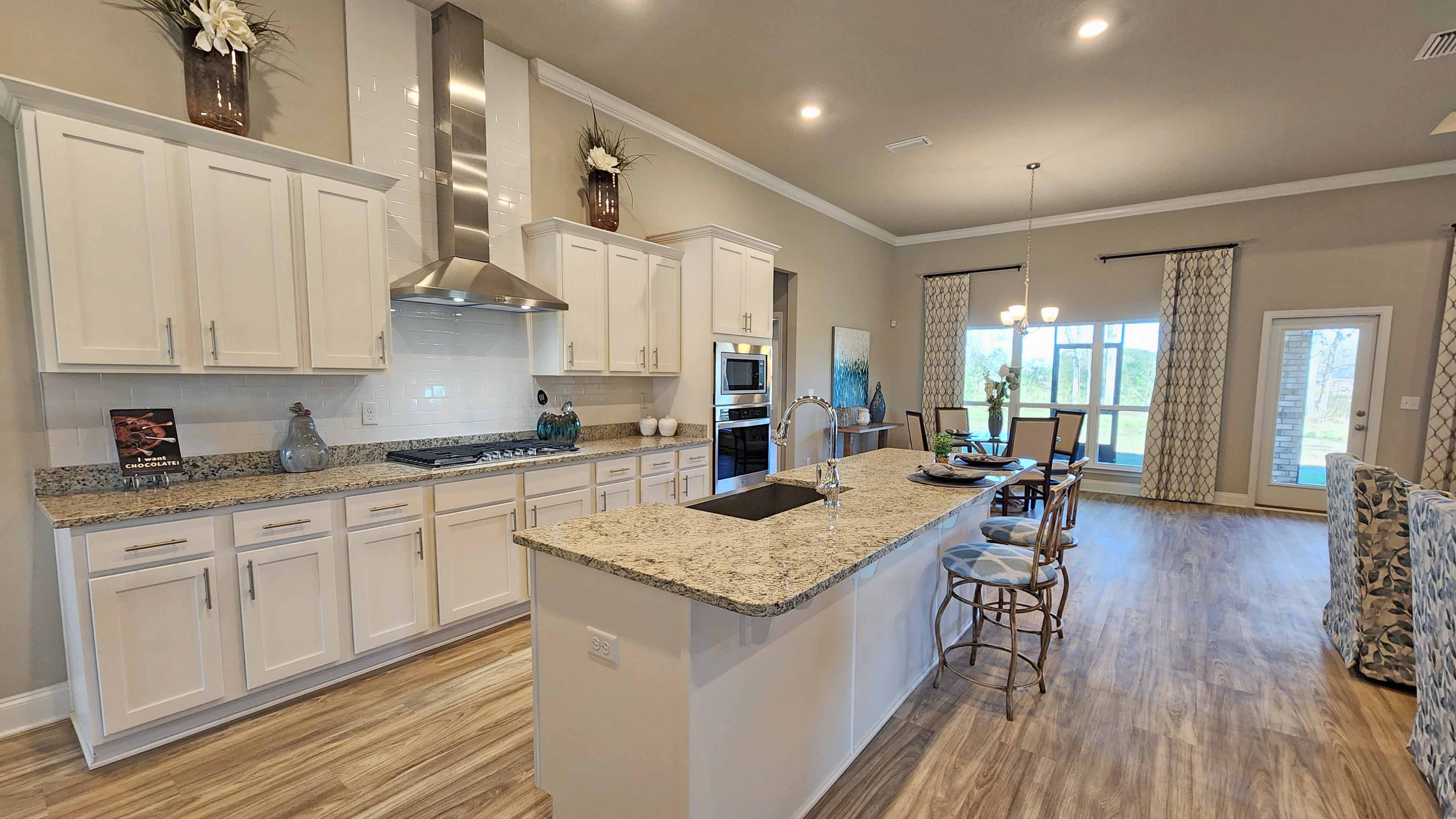 The kitchen with white shaker-style cabinetry and island with additional seating.  .