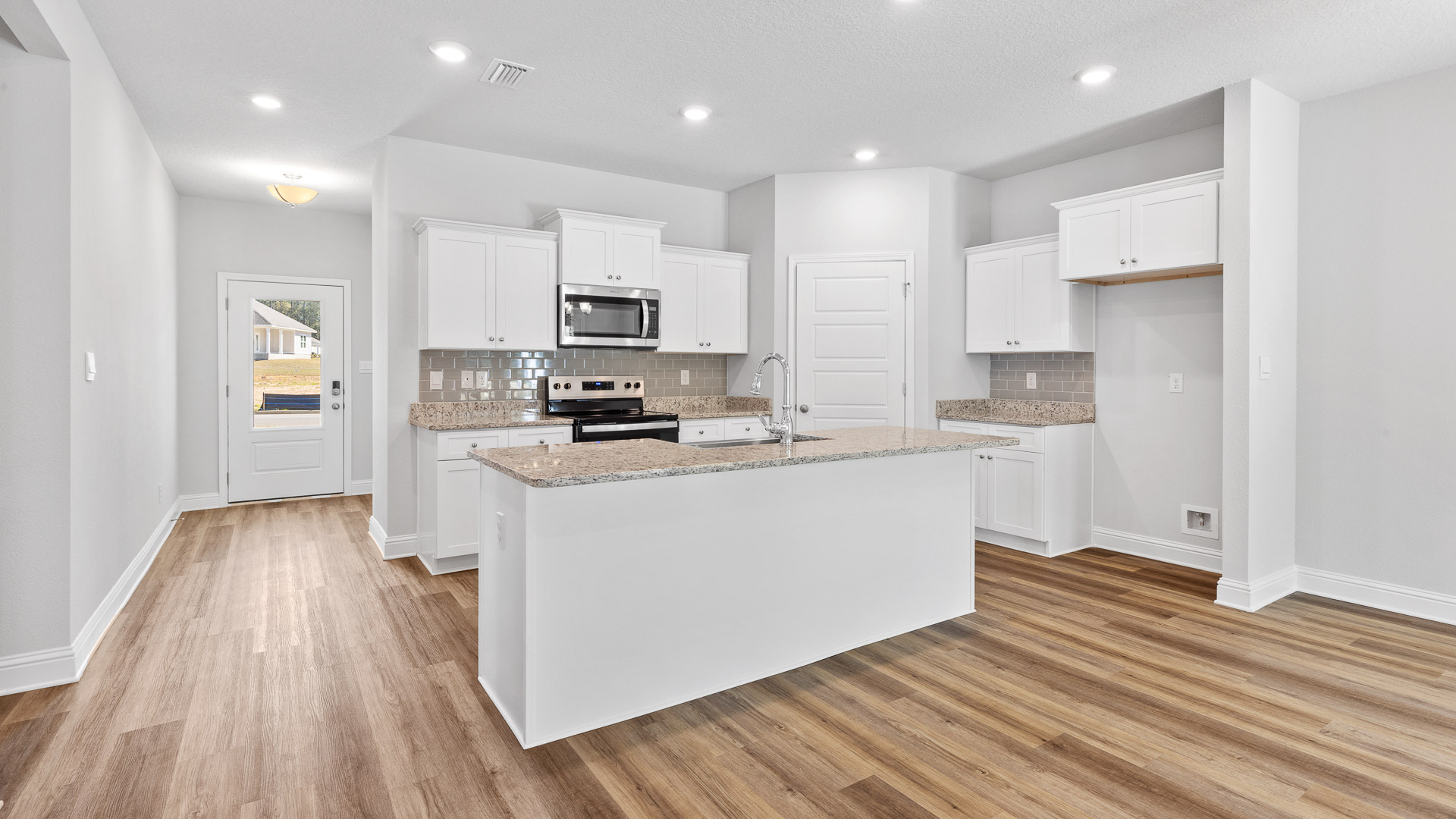 Open kitchen with white cabinets and luxury vinyl plank flooring in Hawkins Manor.
