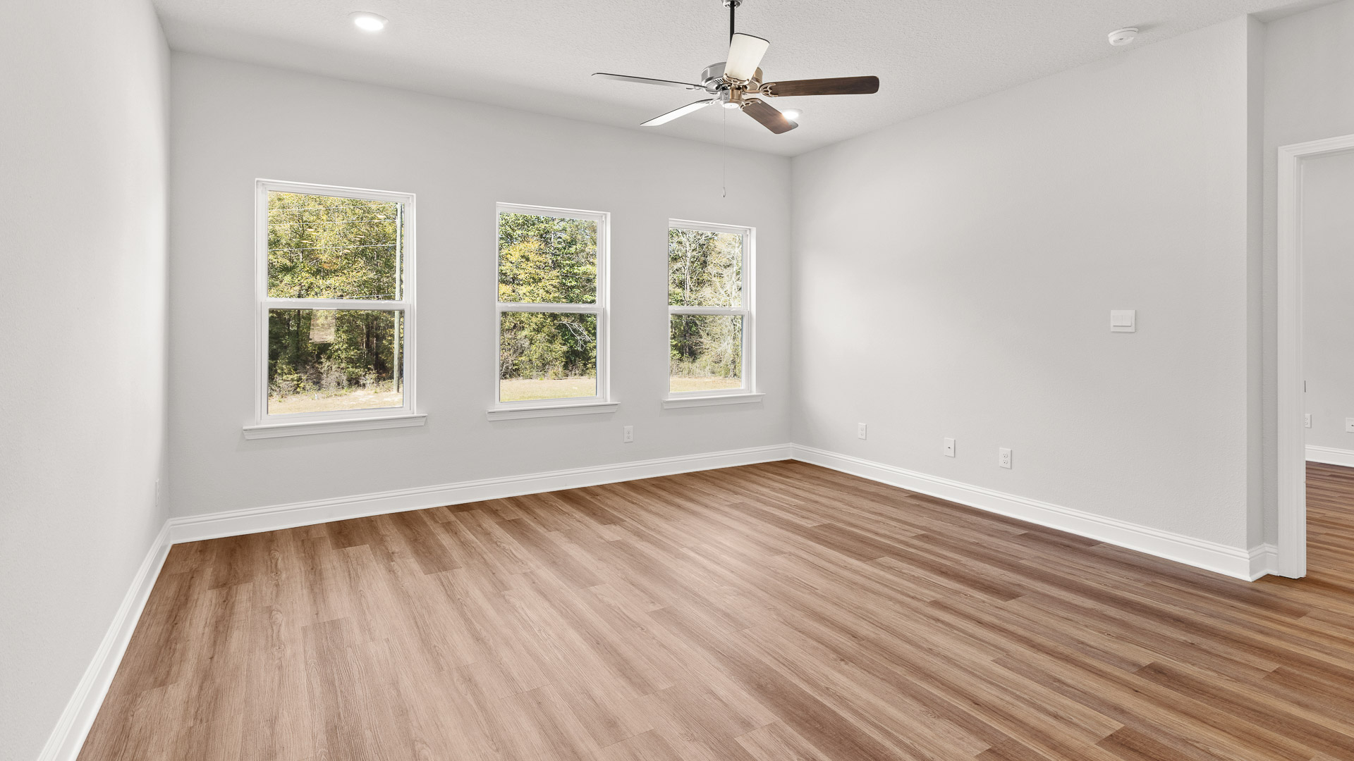 Open living area with high ceilings, luxury vinyl plank flooring and ceiling fan in a new construction home in Mobile.