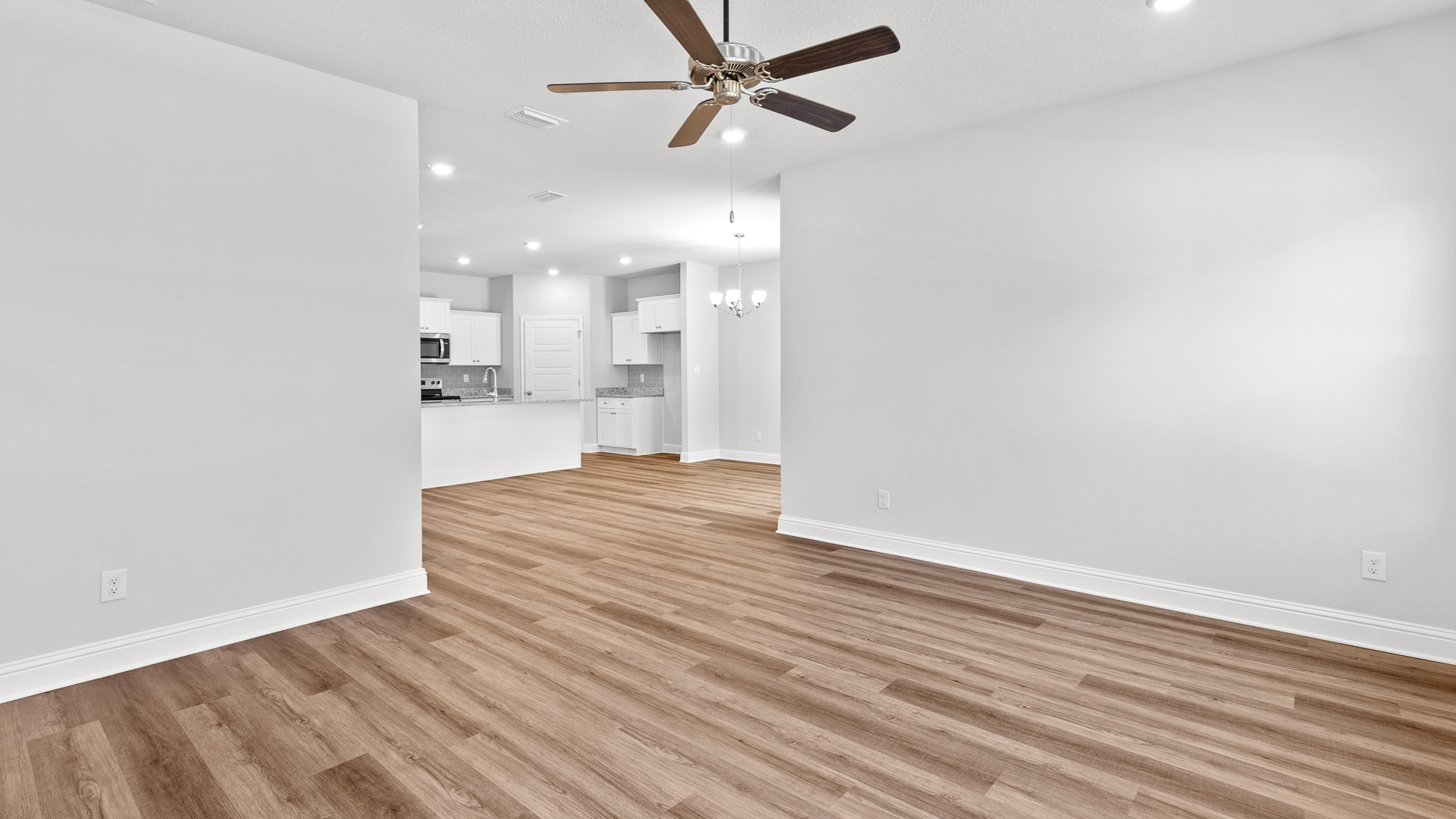 Neutral toned living room with ceiling fan and kitchen view in Hawkins Manor.