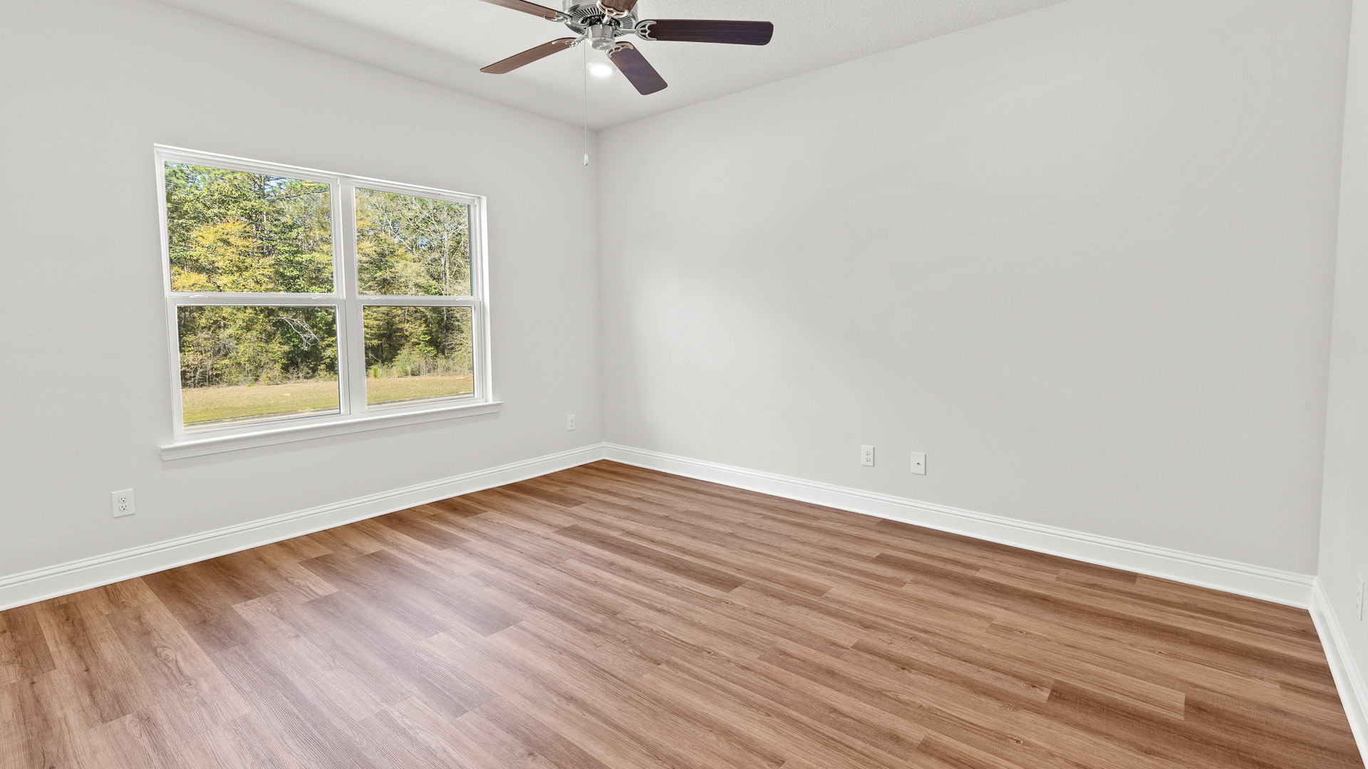 Spacious primary bedroom with large window for natural light and neutral walls in Mobile County.
