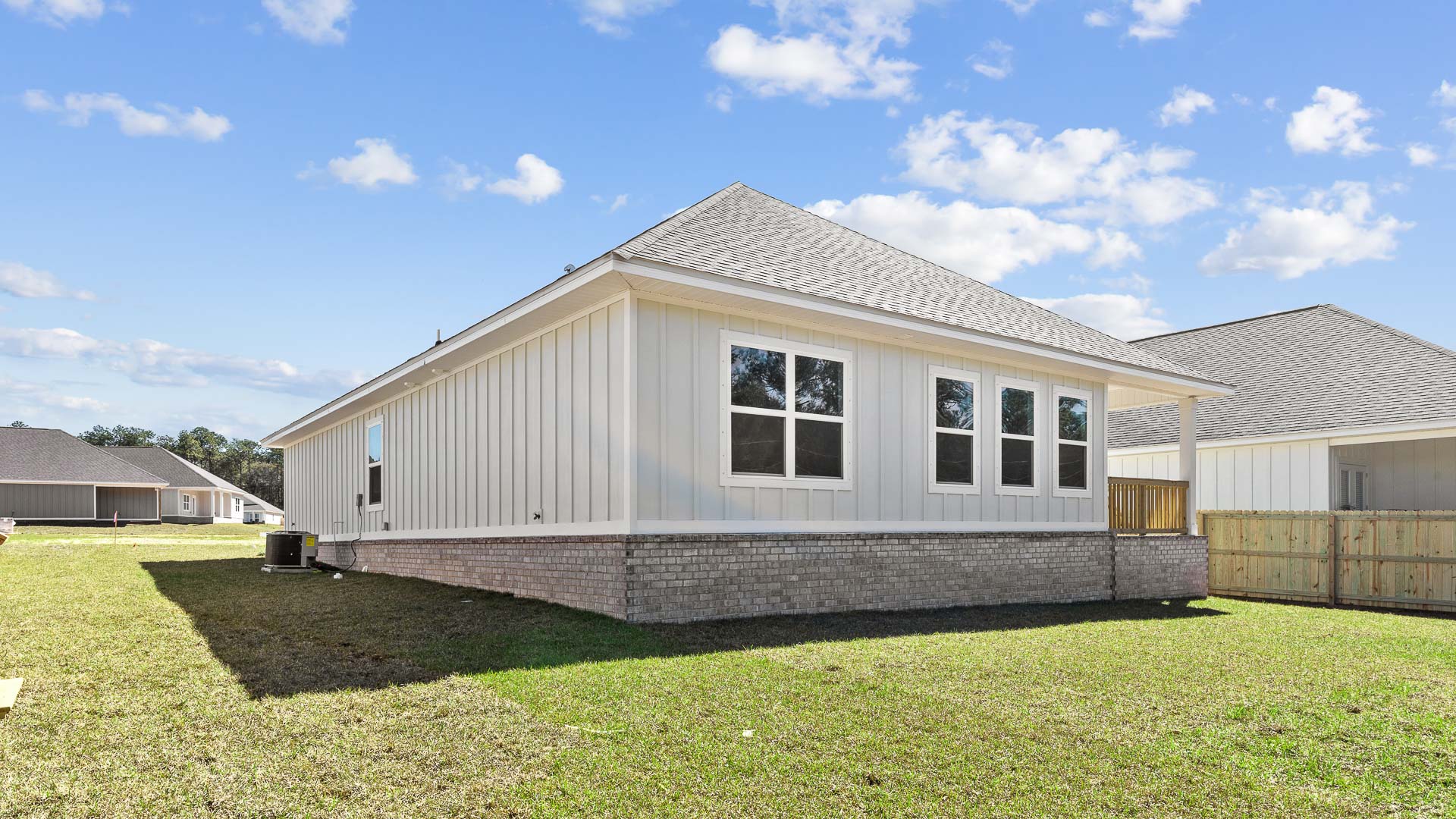 Rear exterior with manicured lawn, hardi plank siding, and brick veneer.