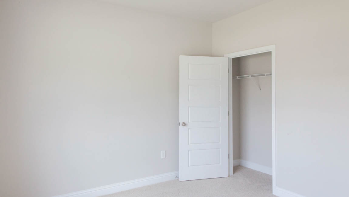 The Bristol guest bedroom with white trim and neutral walls in a new home.
