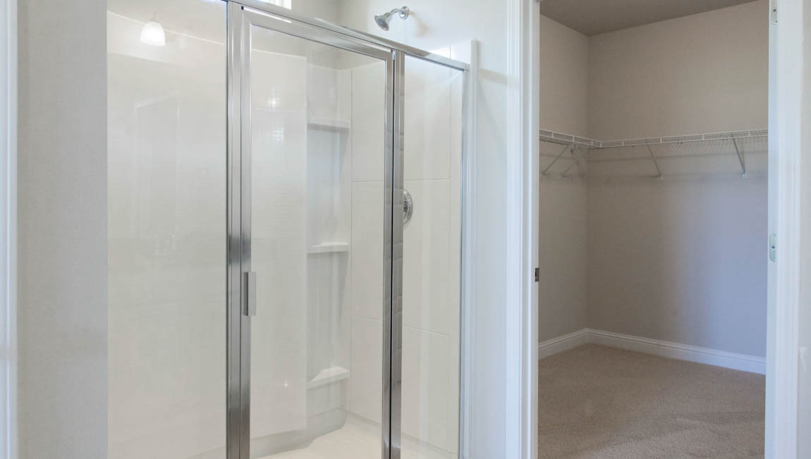 Large primary walk in shower with glass door in ensuite primary bathroom by DR Horton.