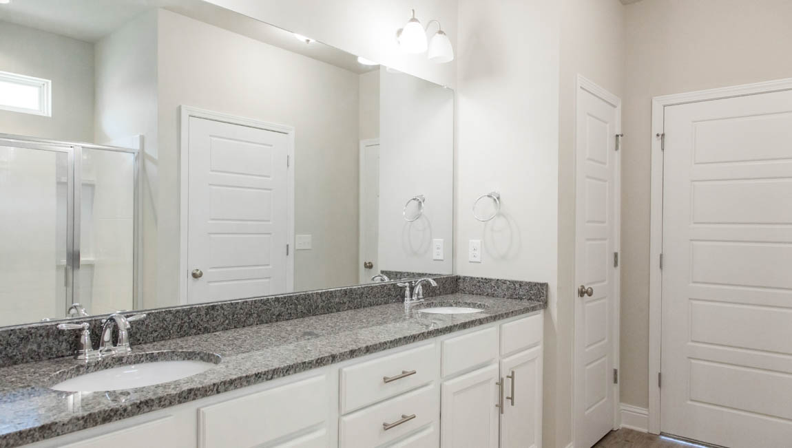 Modern ensuite bathroom with double vanities and ample storage.