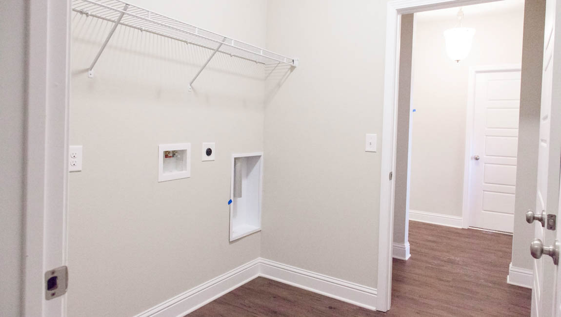 Bright laundry room with luxury vinyl plank flooring and white trim in Mobile County.