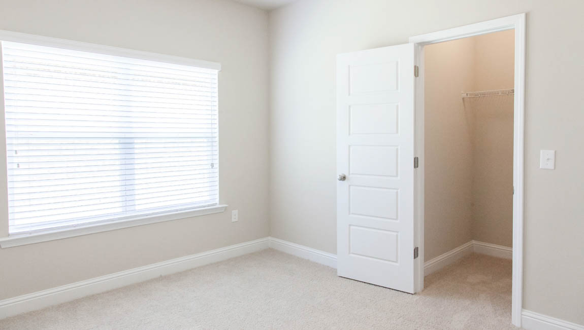 New construction guest bedroom with soft lighting and white trim built by D.R. Horton.