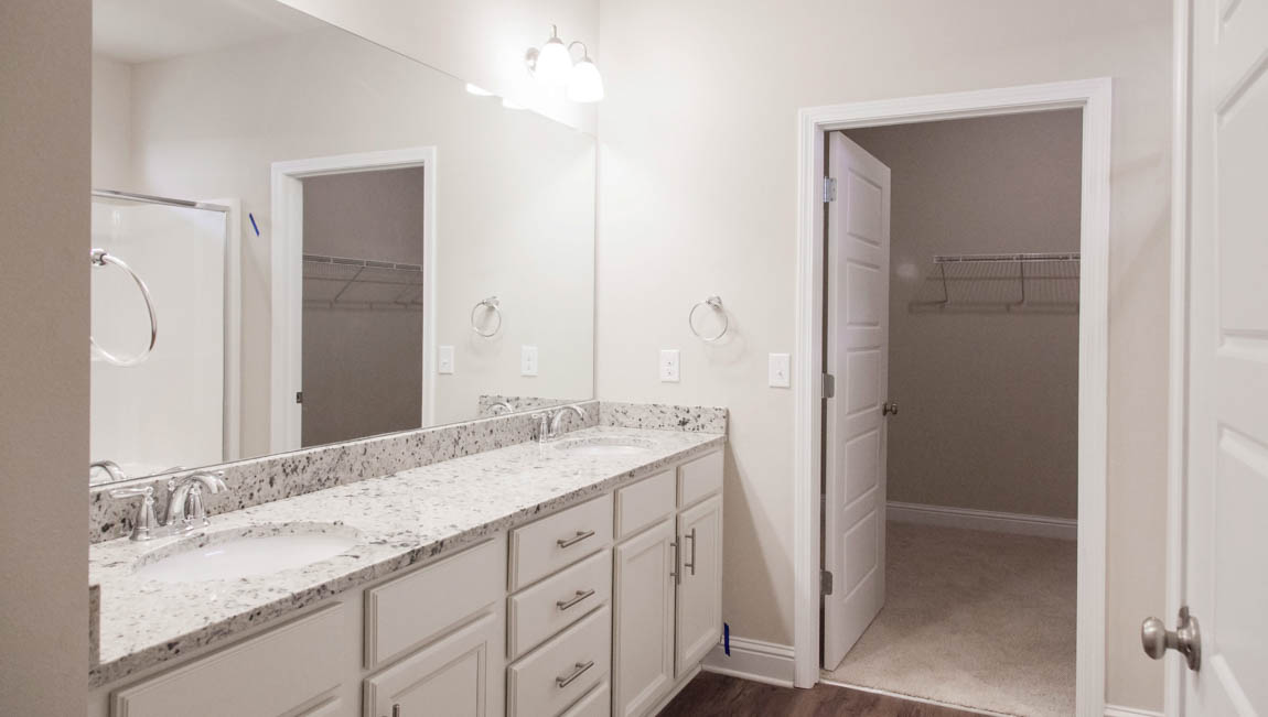 Luxurious primary ensuite with double vanities, undermount sinks, and bath accessories in Mobile County.